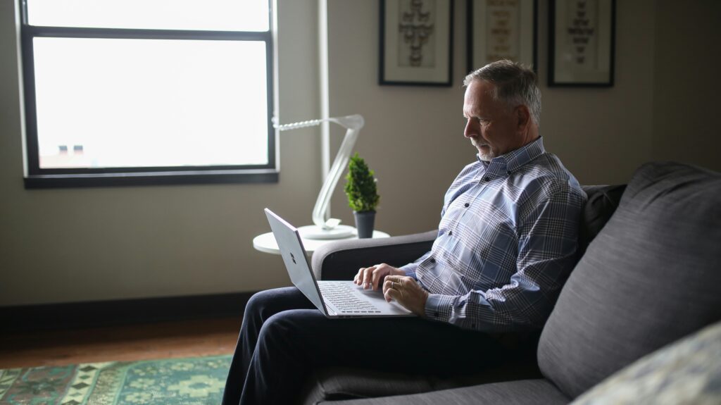 Person in their 50s starting a blog for the first time on a laptop at their kitchen table with morning coffee
